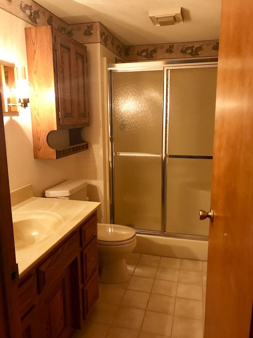 Your private bathroom features a spacious shower, warm wood cabinetry, and thoughtful lighting for comfortable morning and evening routines.
