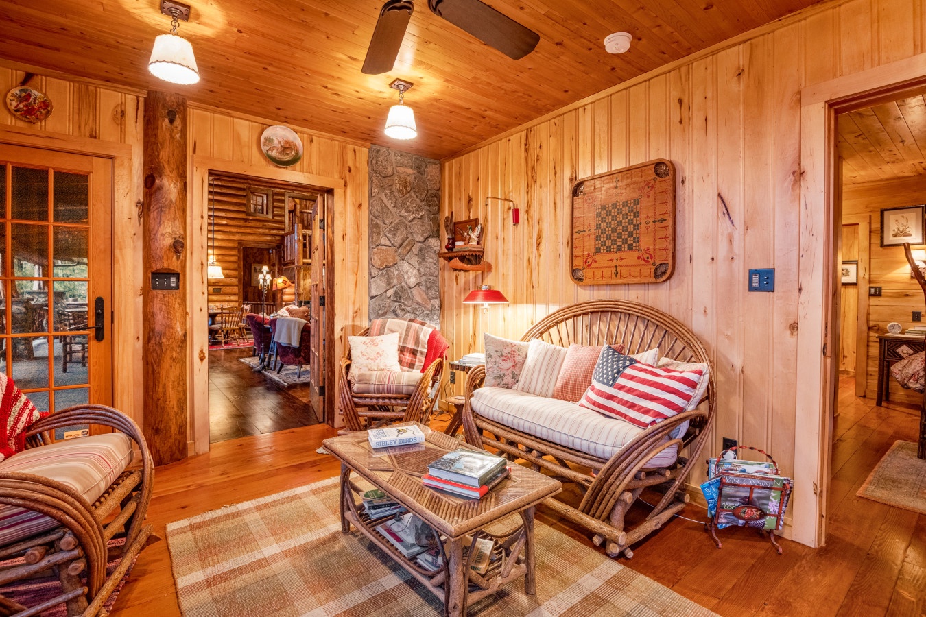 Cozy up in this warm cabin living room with wicker furniture, rustic wood walls, and charming game boards.