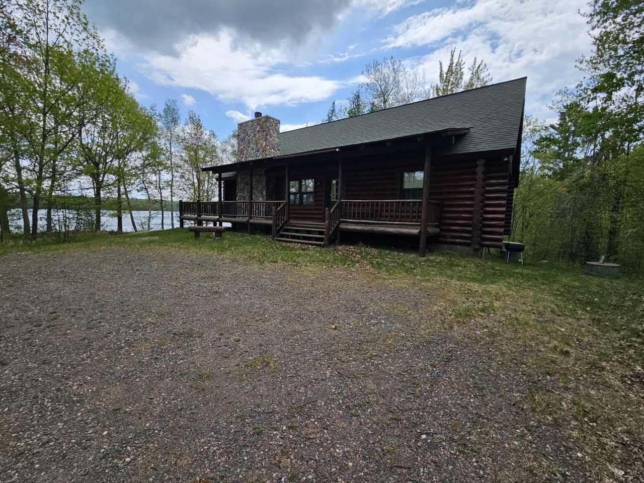 Rustic log cabin nestled among trees with lakefront access and spacious deck for outdoor relaxation.