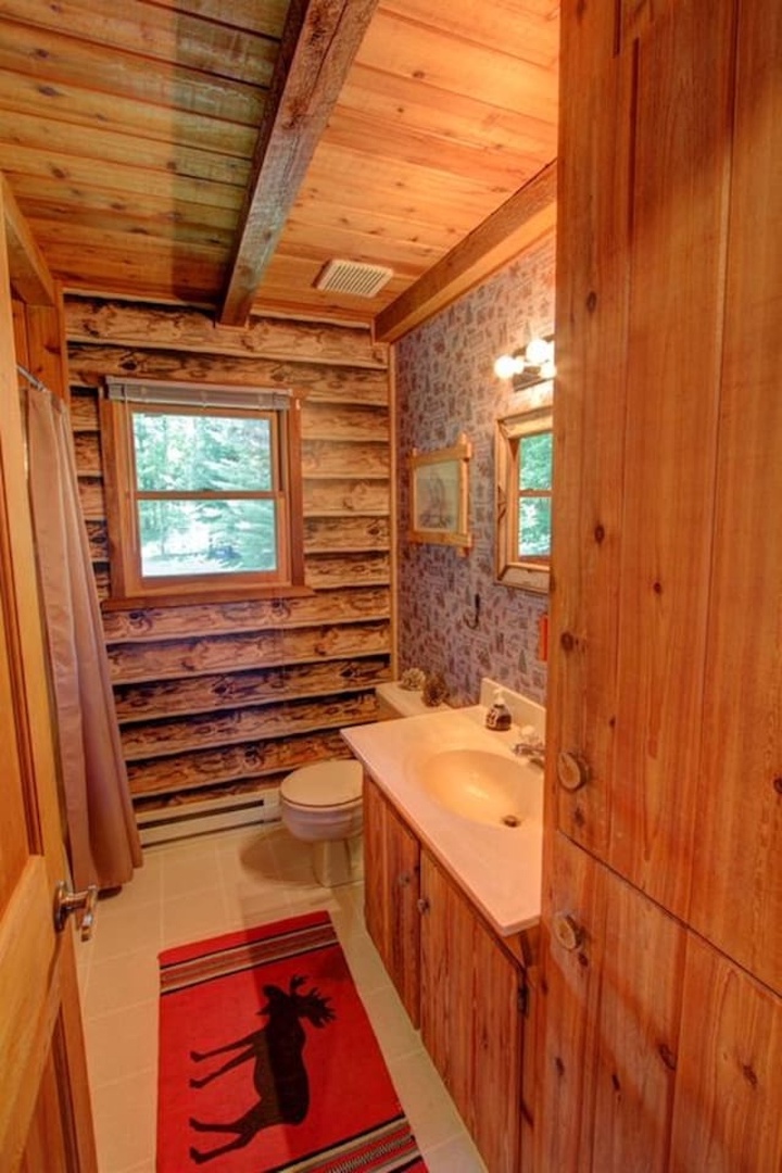 Rustic charm meets comfort in your private bathroom, where warm wood surrounds you and natural light streams through forest views.