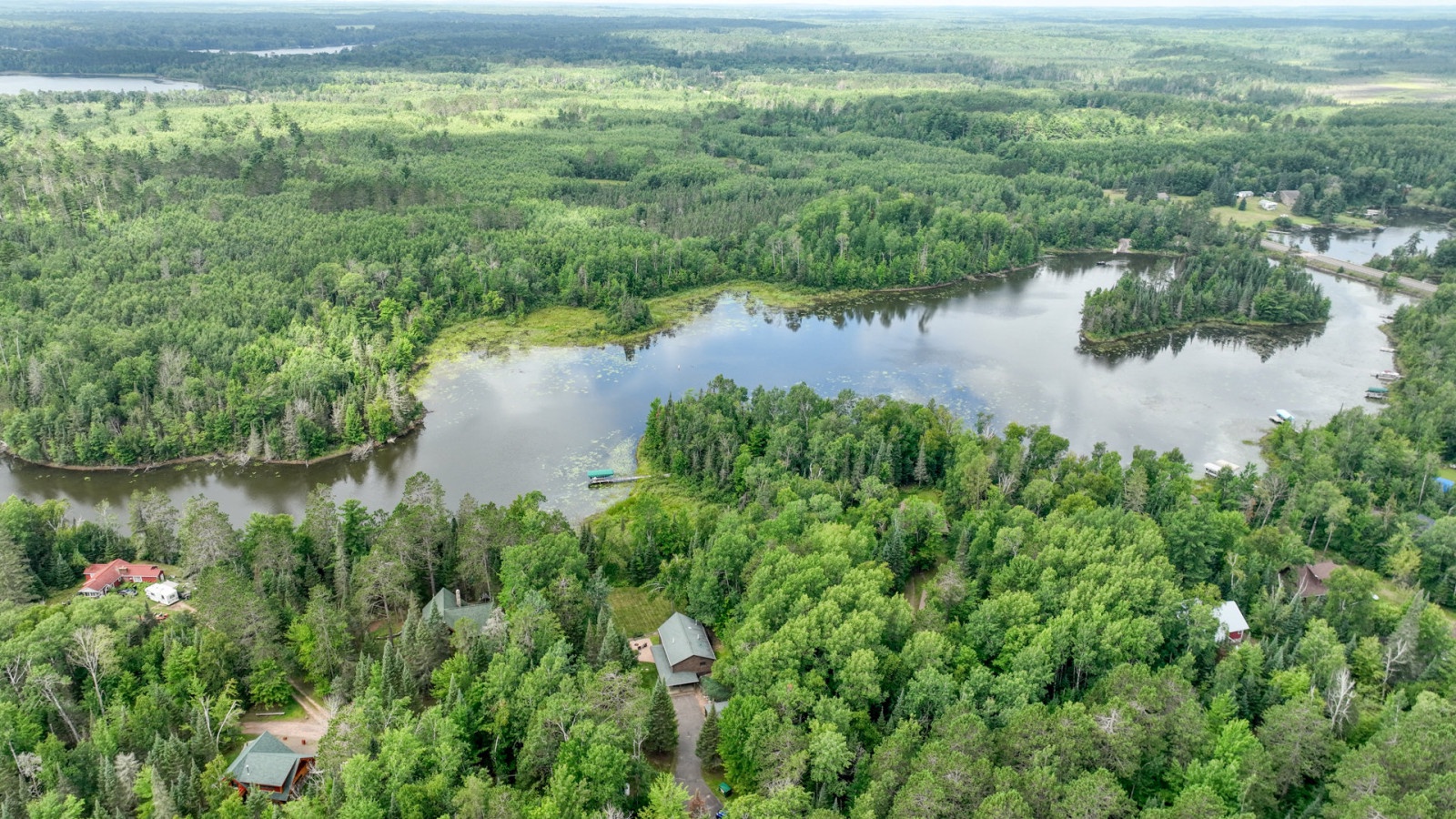 Aerial view showcases pristine lakefront setting surrounded by dense forest, offering peaceful retreat from city life.