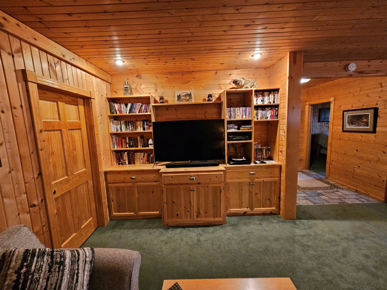 Cozy up in your wood-paneled entertainment center with built-in shelves full of books and games for relaxing evenings.