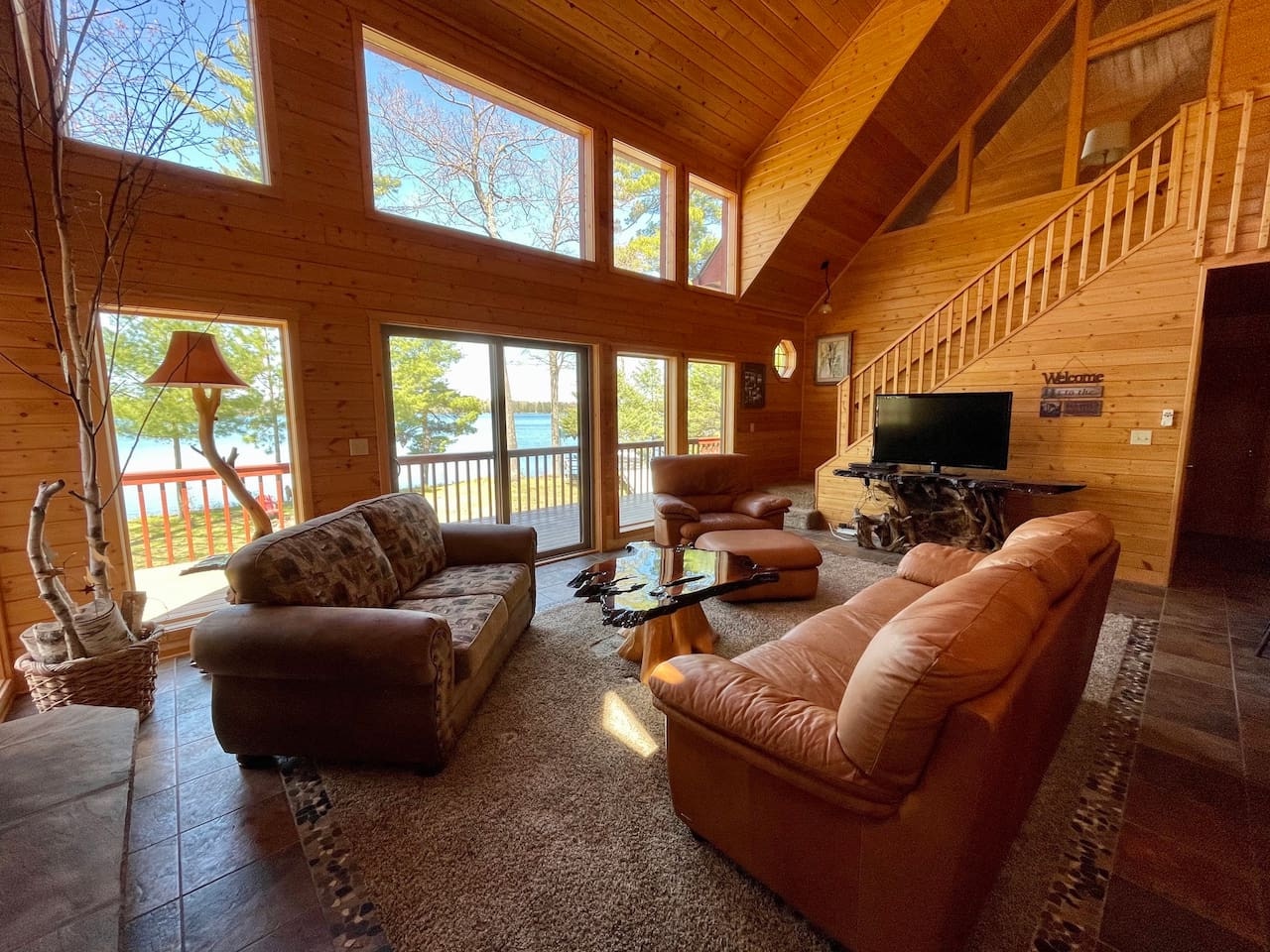 Relax in your spacious living room with vaulted ceilings, leather seating, and stunning lake views through floor-to-ceiling windows.