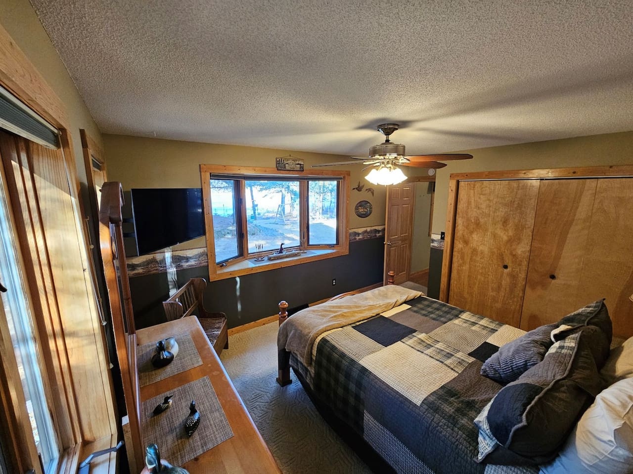 Sink into your comfortable bed while enjoying lake views through the large window. The warm wood details and ceiling fan create a cozy retreat.