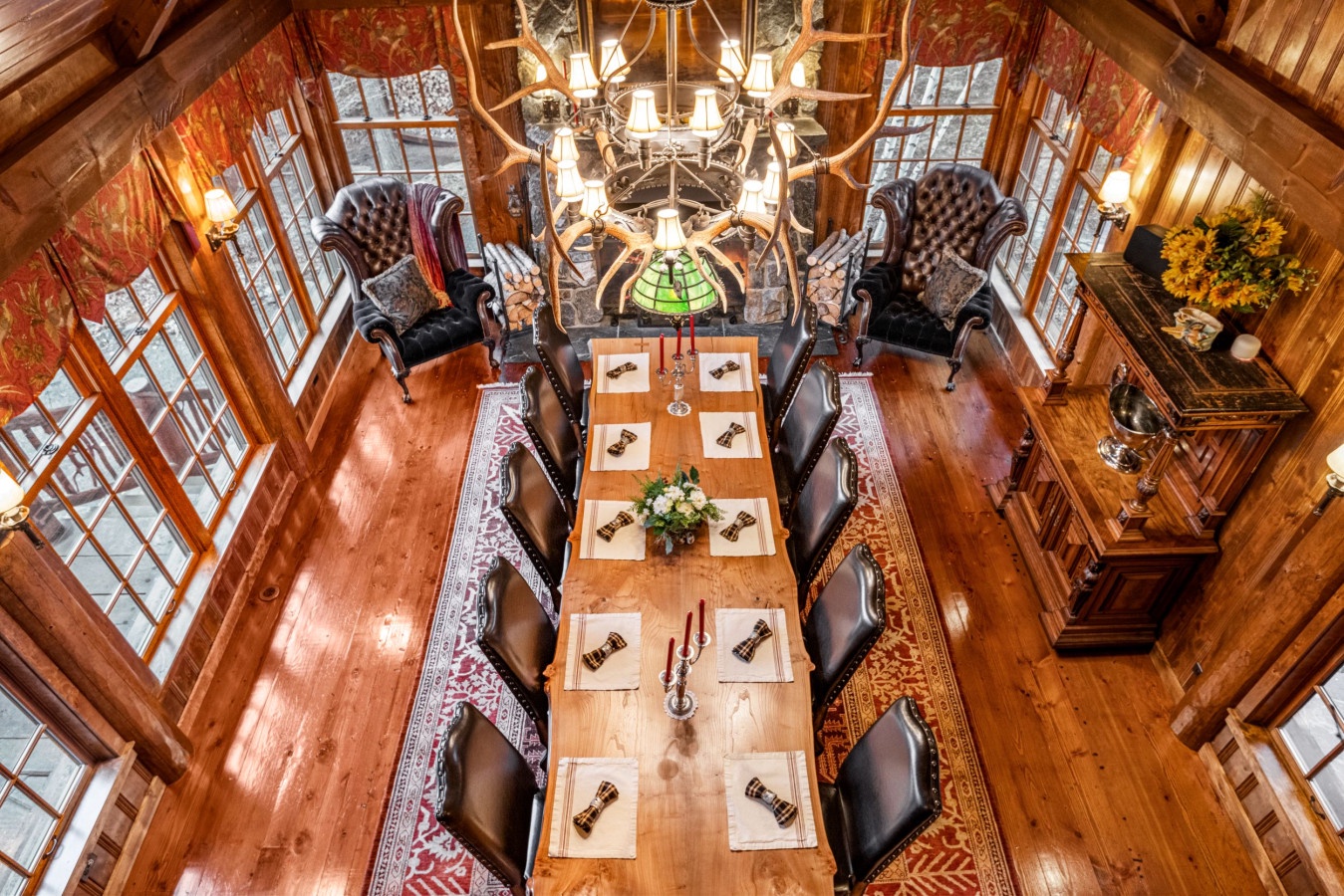 Your elegant dining space features rustic wood beams, antler chandelier, and stone fireplace creating the perfect atmosphere for memorable meals.