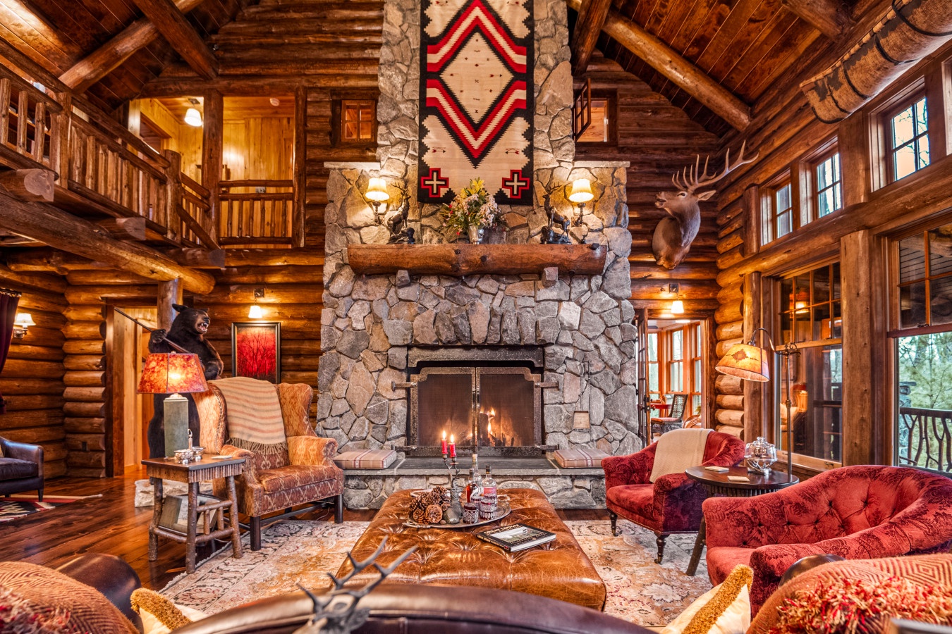 Gather around the crackling stone fireplace in this stunning log cabin living room, where rustic charm meets cozy luxury for unforgettable evenings.