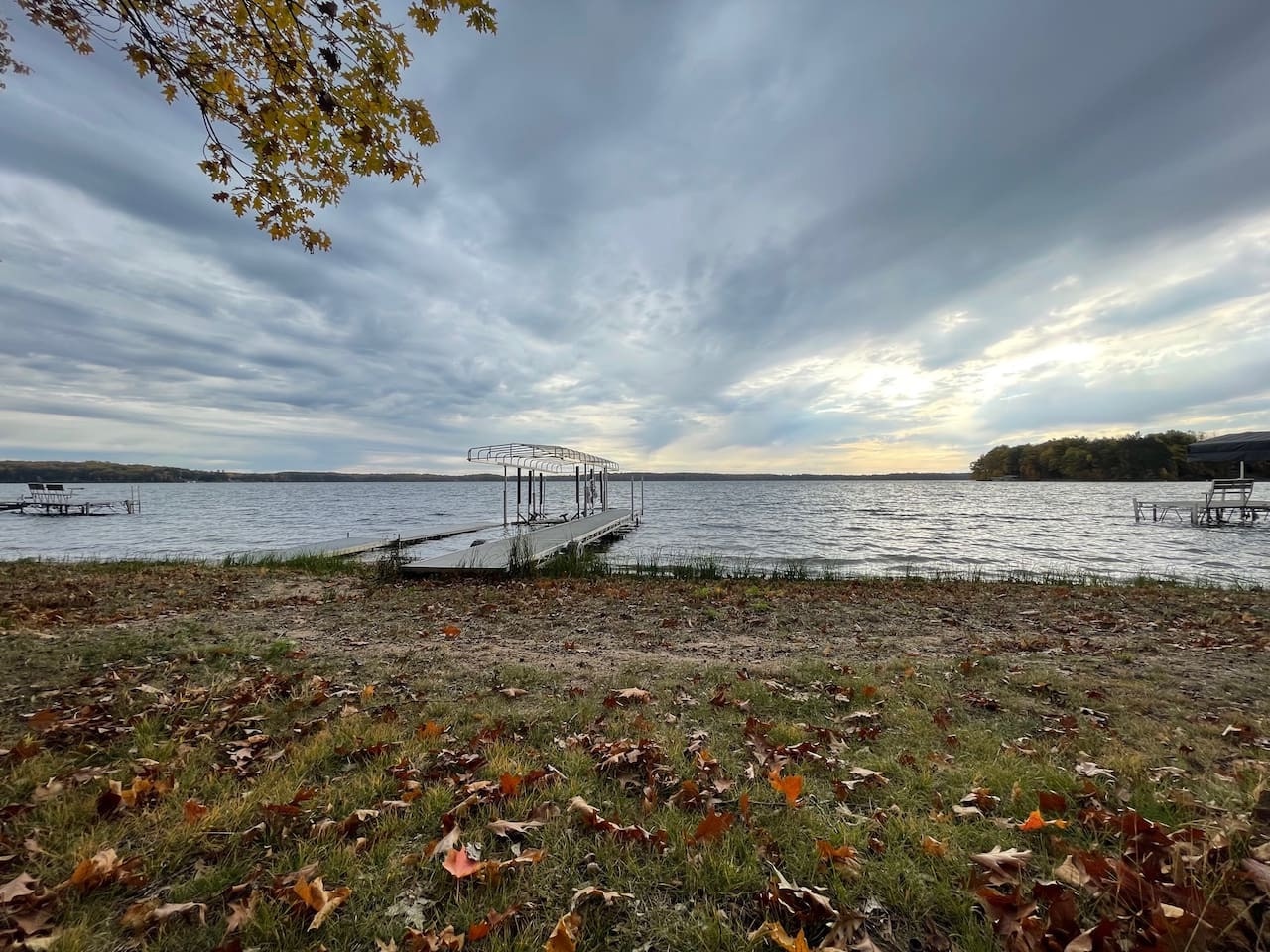 Peaceful lakefront setting with private dock and autumn foliage creating a serene waterfront retreat.