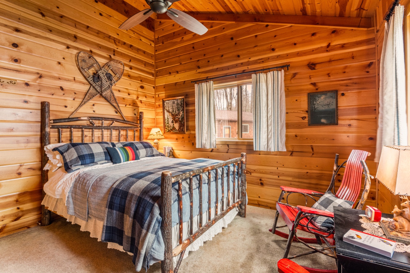 Cozy log cabin bedroom with rustic wooden walls, vintage snowshoes, and plaid bedding creates your perfect mountain retreat atmosphere.