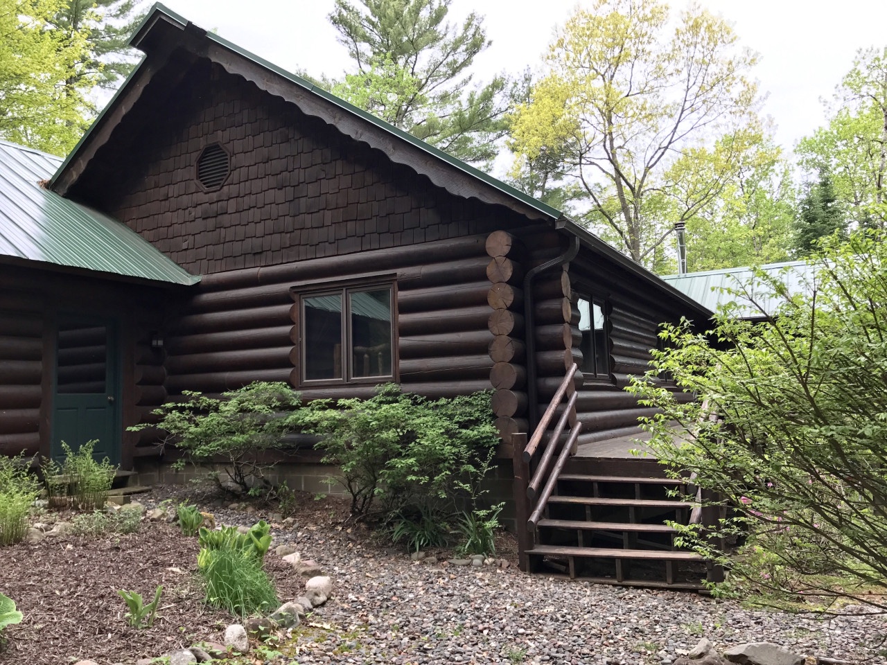 Rustic log cabin nestled among towering trees, featuring natural wood construction and peaceful woodland surroundings.