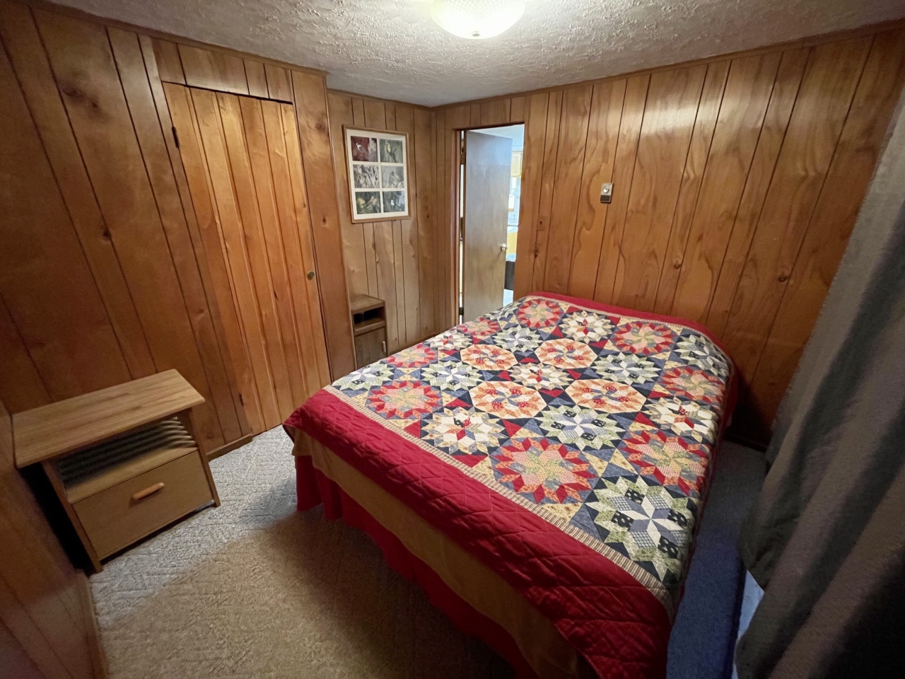 Drift off to sleep wrapped in this charming handmade quilt in your cozy wood-paneled bedroom, where rustic warmth meets comfort.