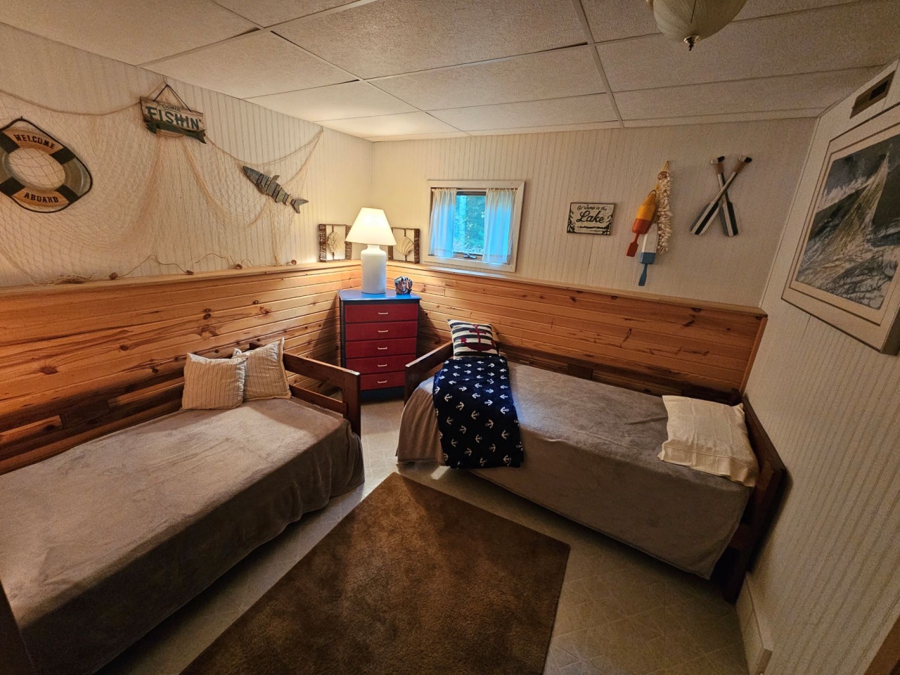 Drift off in your charming nautical bedroom featuring twin beds, rustic wood paneling, and maritime décor that captures the spirit of coastal adventures.