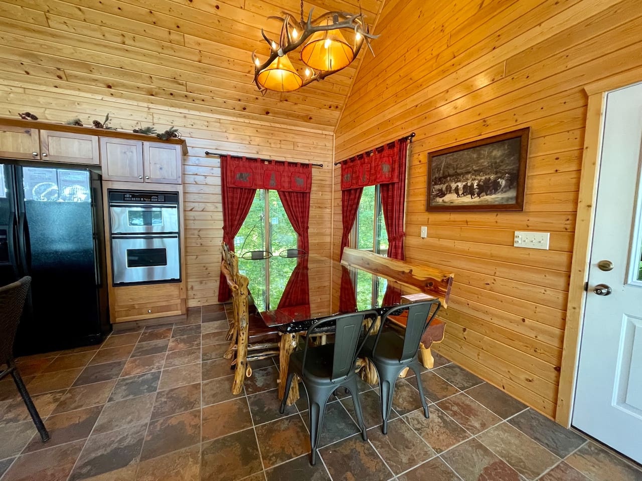 Your rustic dining space features warm wood walls and a cozy table where you'll enjoy meals surrounded by cabin charm and nature views.