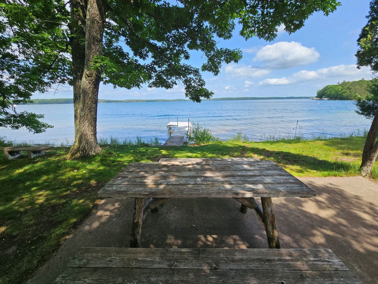 Enjoy lakefront dining at your private picnic table, where dappled sunlight filters through ancient trees and peaceful waters stretch endlessly before you.