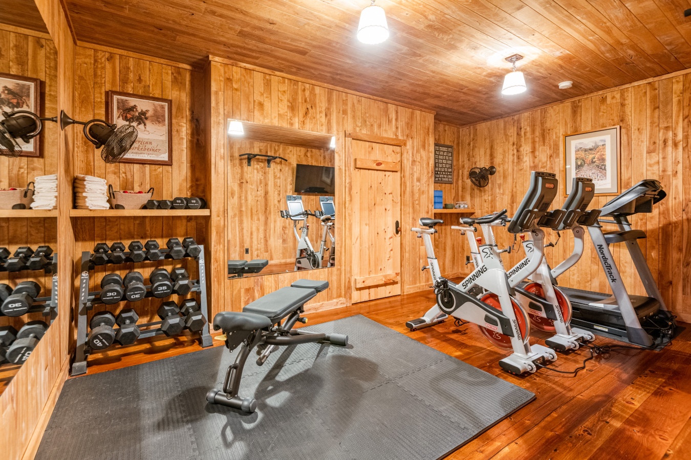 Your private fitness retreat awaits with rustic wood charm, complete weights, cardio equipment, and towels ready for your workout.