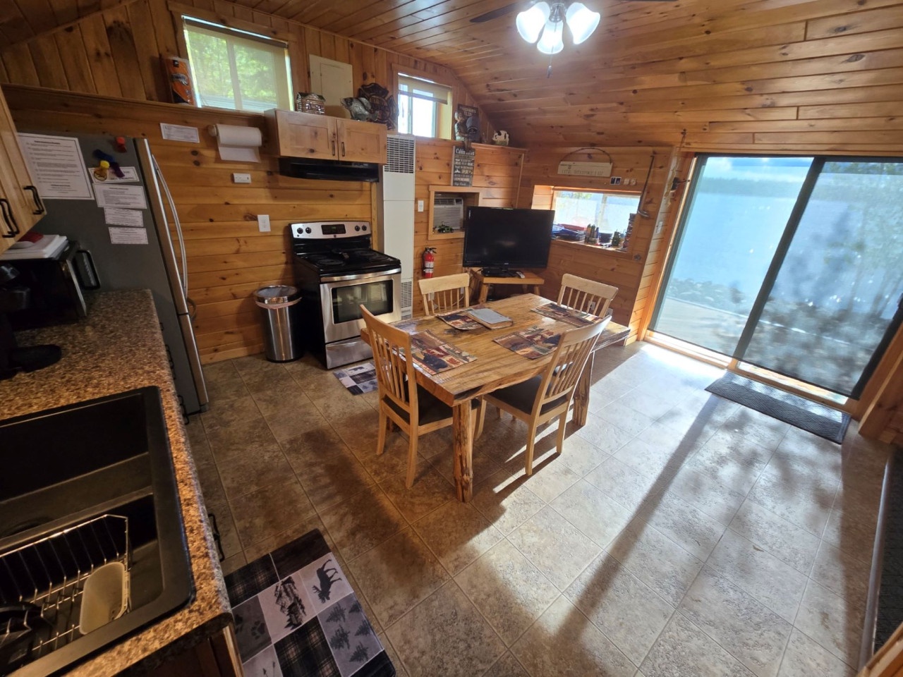 Gather around the rustic dining table in this cozy cabin kitchen, where wood-paneled walls create warmth for your memorable meals together.