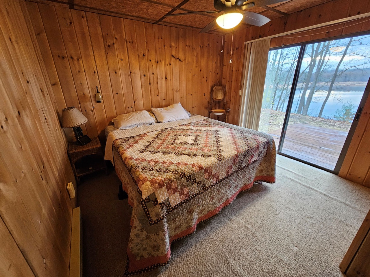 Cozy cabin bedroom with rustic wood walls where your handmade quilt awaits peaceful lakeside slumber.
