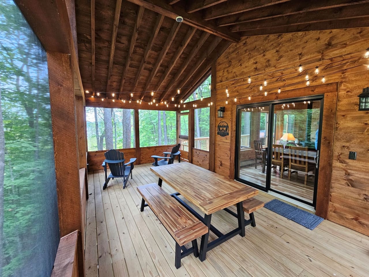 Relax on your private covered deck with dining table and forest views. String lights create perfect ambiance for evening meals outdoors.