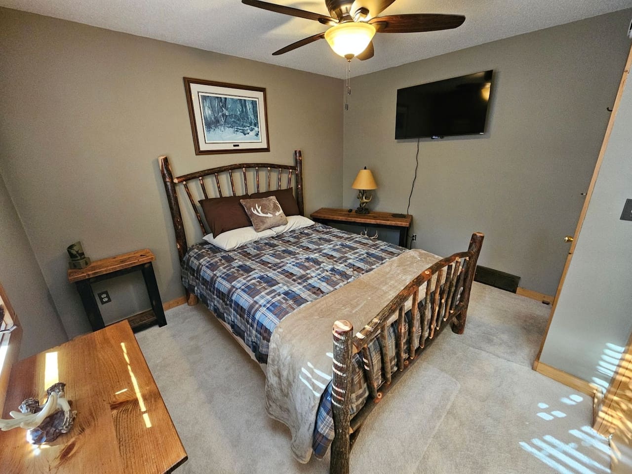 Rest easy in your cozy bedroom with rustic wood furnishings, soft carpeting, and modern TV entertainment for perfect relaxation.