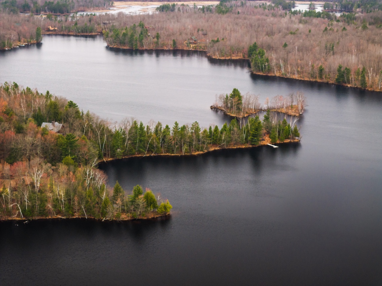 Aerial view showcasing pristine lake waters surrounded by forested peninsulas and natural wilderness in the surrounding area.