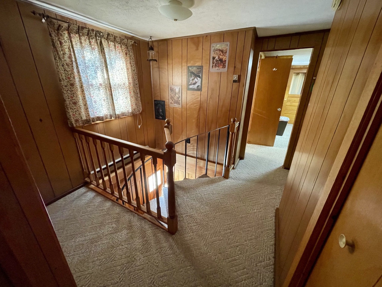 Step into your cozy retreat where warm wood paneling creates a homey atmosphere. The charming stairway leads to comfortable spaces above.