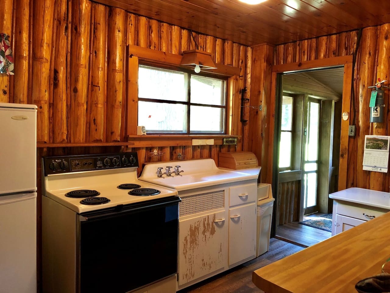 Step into your rustic kitchen where warm wood surrounds you completely. Cook meals on the vintage stove while natural light streams through charming windows.