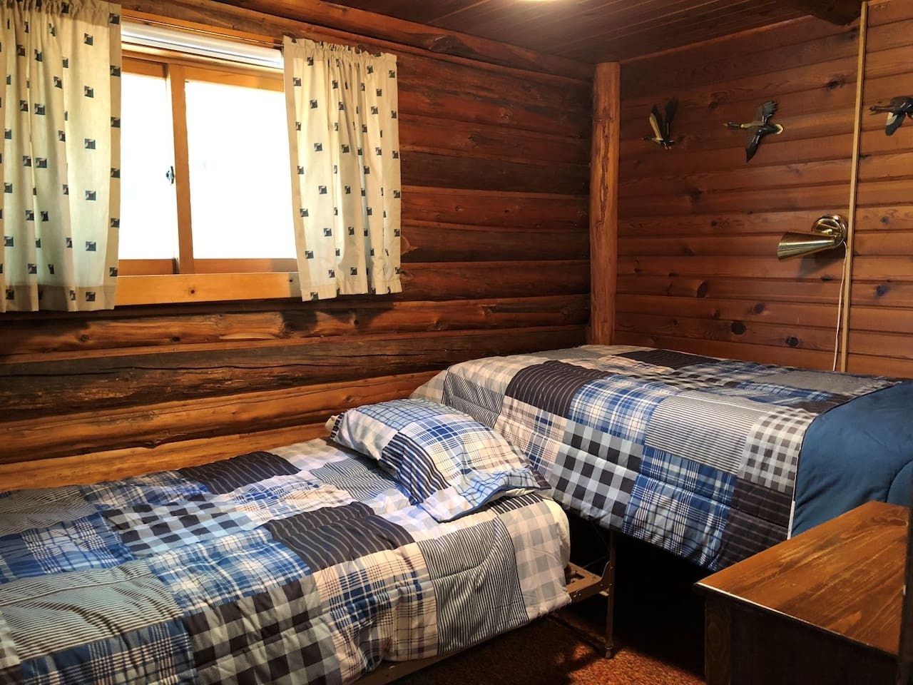 Your cozy cabin bedroom wraps you in warm wood walls and rustic charm. Plaid bedding invites restful nights after mountain adventures.