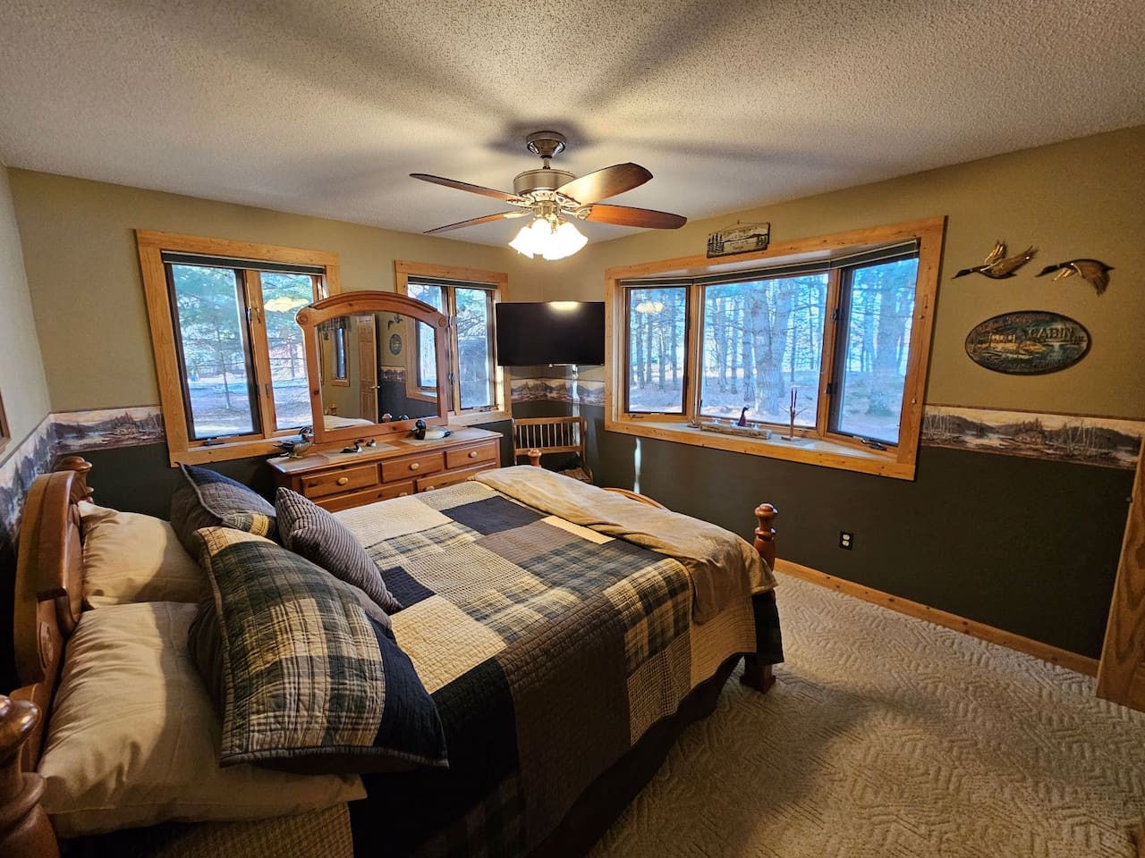 Rest peacefully in your cozy cabin bedroom, where rustic charm meets modern comfort with forest views through every window.