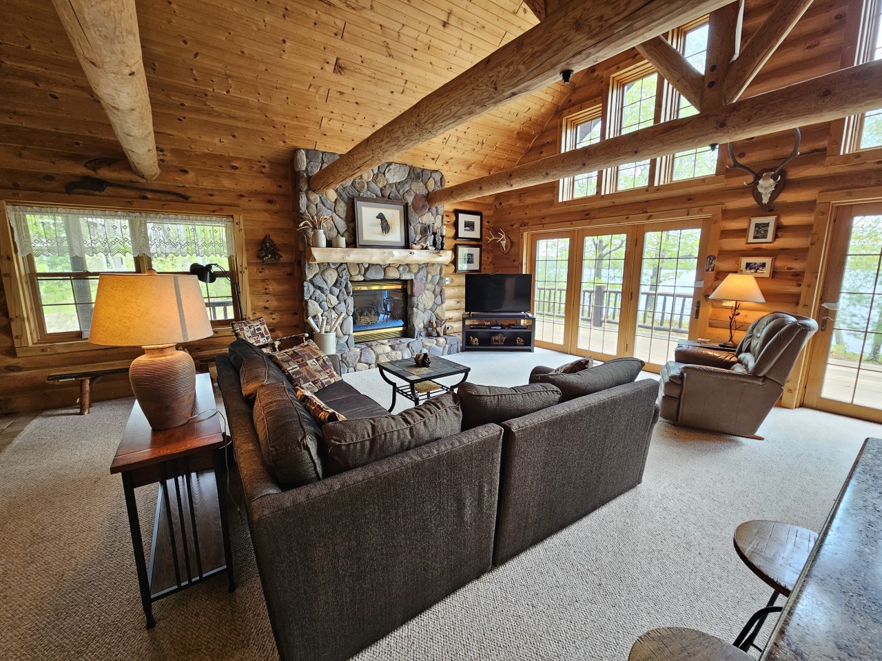 Unwind in your cozy cabin living room with soaring wood ceilings, stone fireplace, and plush seating for movie nights.