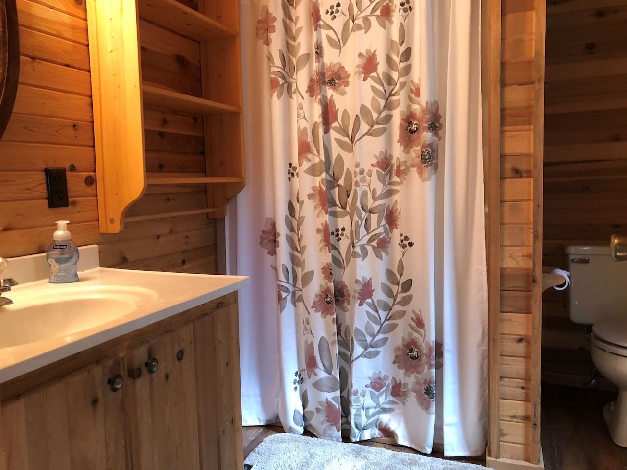 Step into your charming rustic bathroom with beautiful floral shower curtain and warm wood finishes throughout.