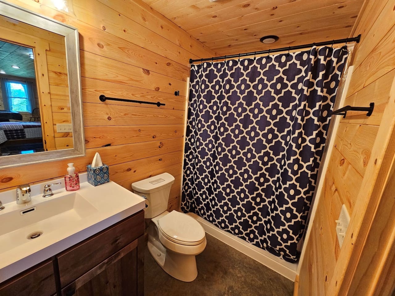 Step into your rustic bathroom with warm wood walls, modern fixtures, and a stylish patterned shower curtain for your private retreat.
