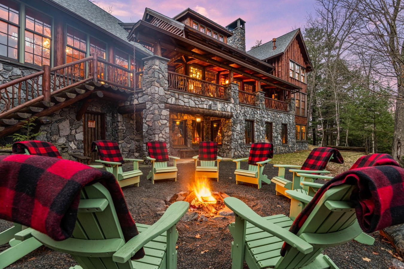Gather around this cozy fire pit with soft plaid blankets, sharing stories under the twilight sky at this stunning mountain lodge.