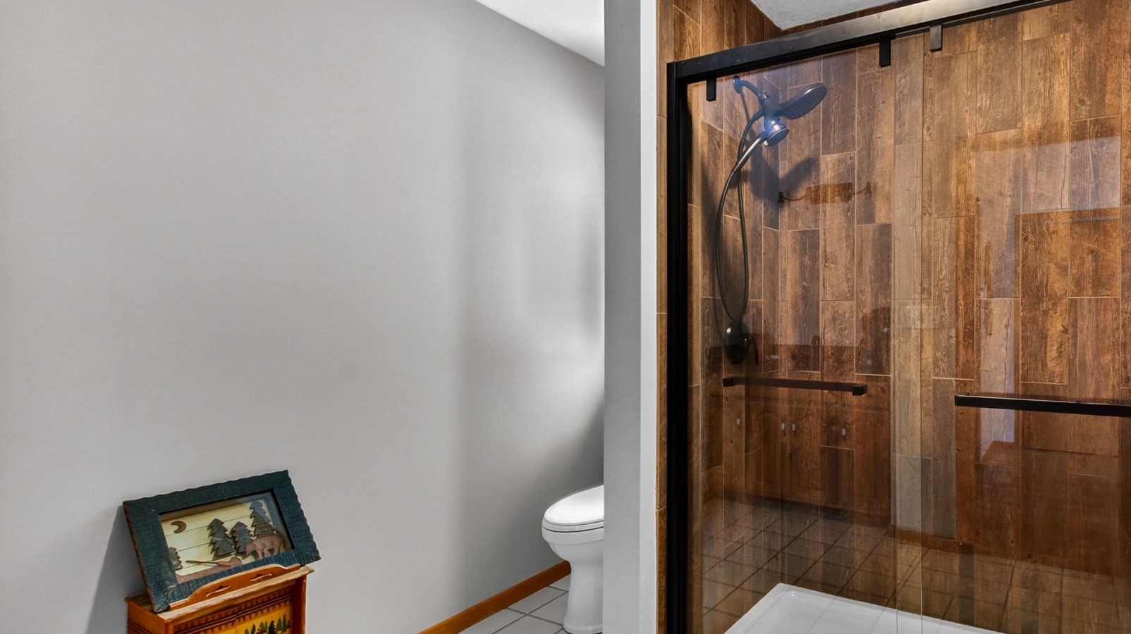 Step into your private bathroom featuring a spacious walk-in shower with beautiful wood-look tile and modern black fixtures.