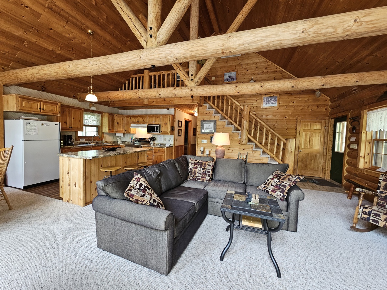 Relax in your cozy log cabin with soaring timber beams, a fully equipped kitchen, and comfortable seating perfect for mountain getaways.