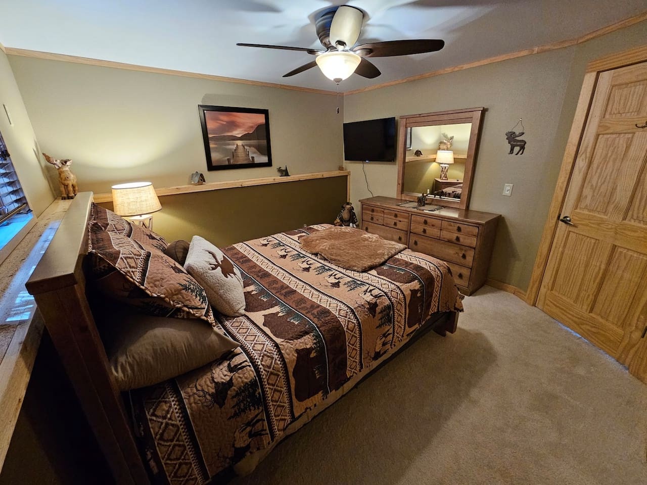 Drift into peaceful sleep in your cozy rustic bedroom, complete with charming wildlife decor, warm lighting, and modern TV entertainment.