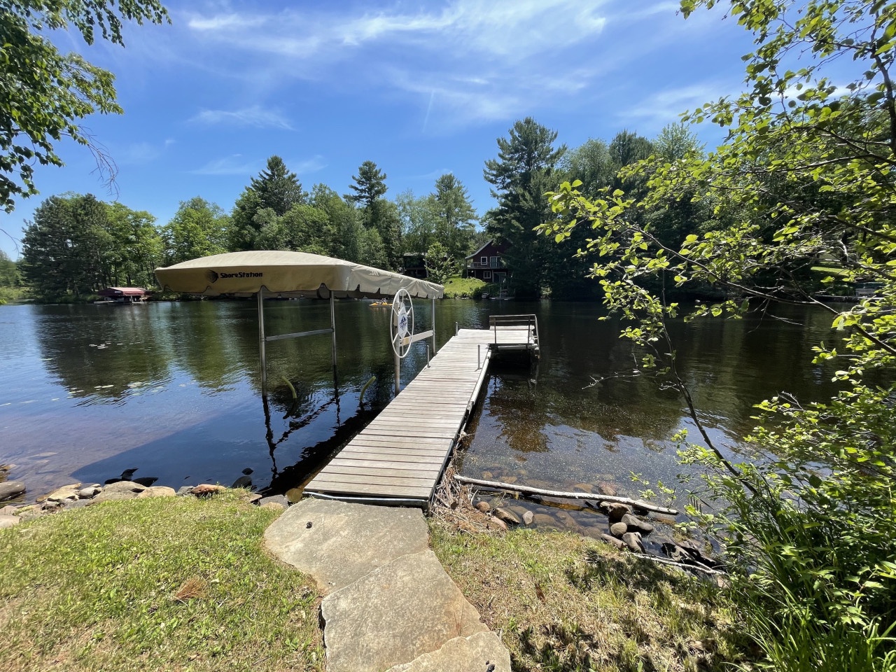 Private dock extends into calm lake waters, surrounded by mature trees and peaceful natural setting.