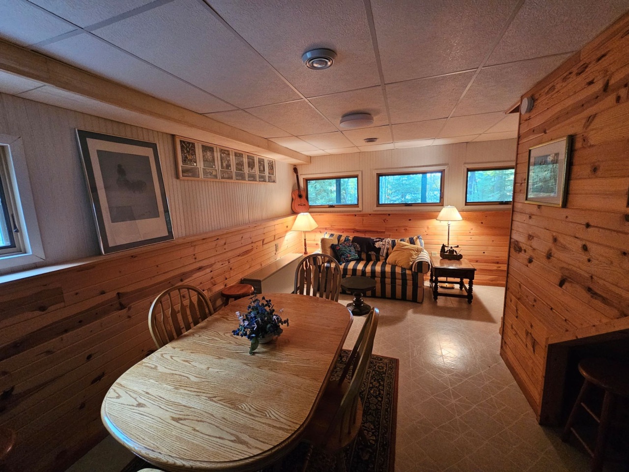 Settle into your cozy basement retreat, where warm wood paneling and comfortable seating create the perfect space for family meals and relaxation.