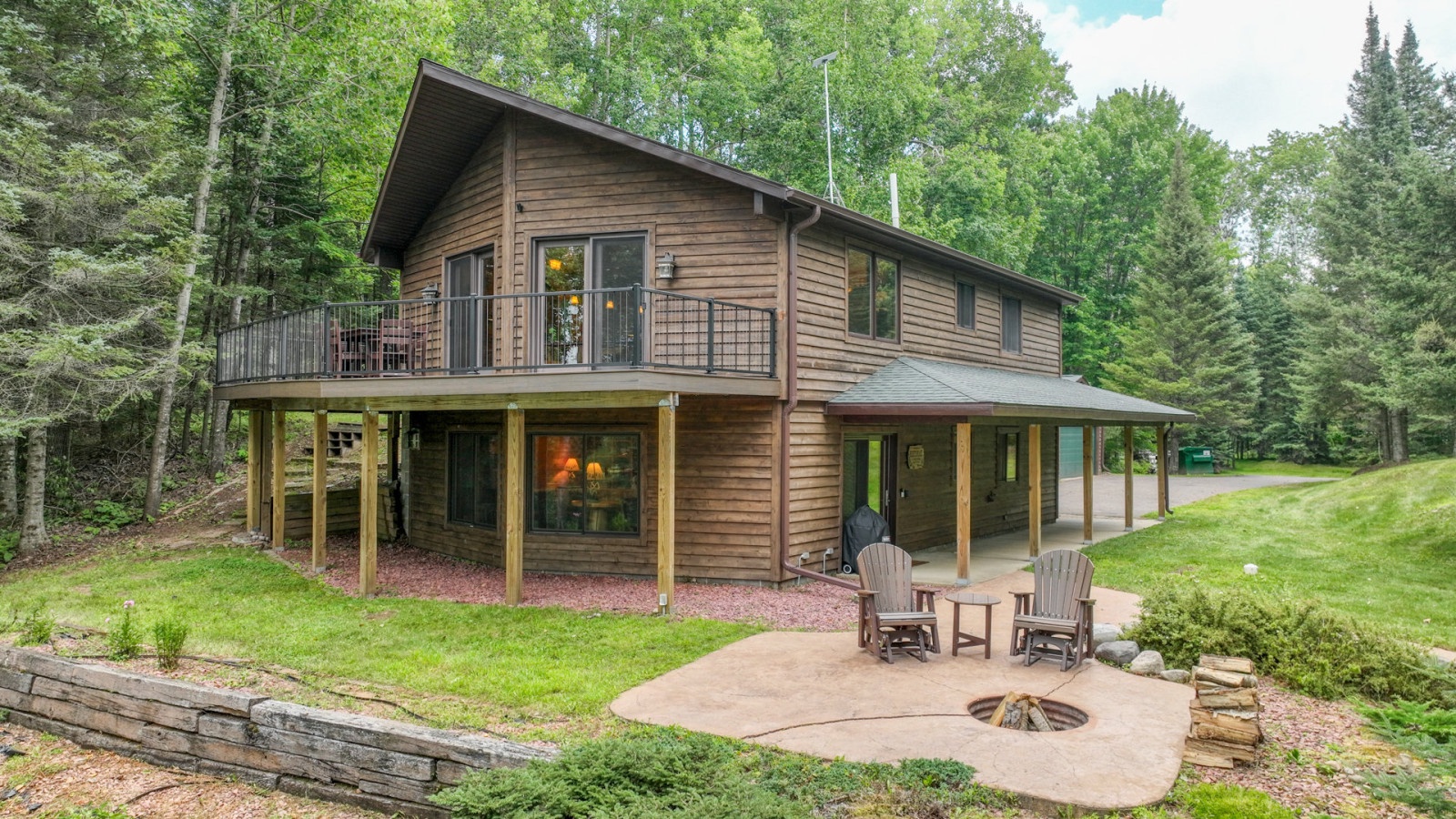 A charming cedar cabin nestled among towering trees, featuring a wraparound deck and private fire pit for cozy evenings outdoors.