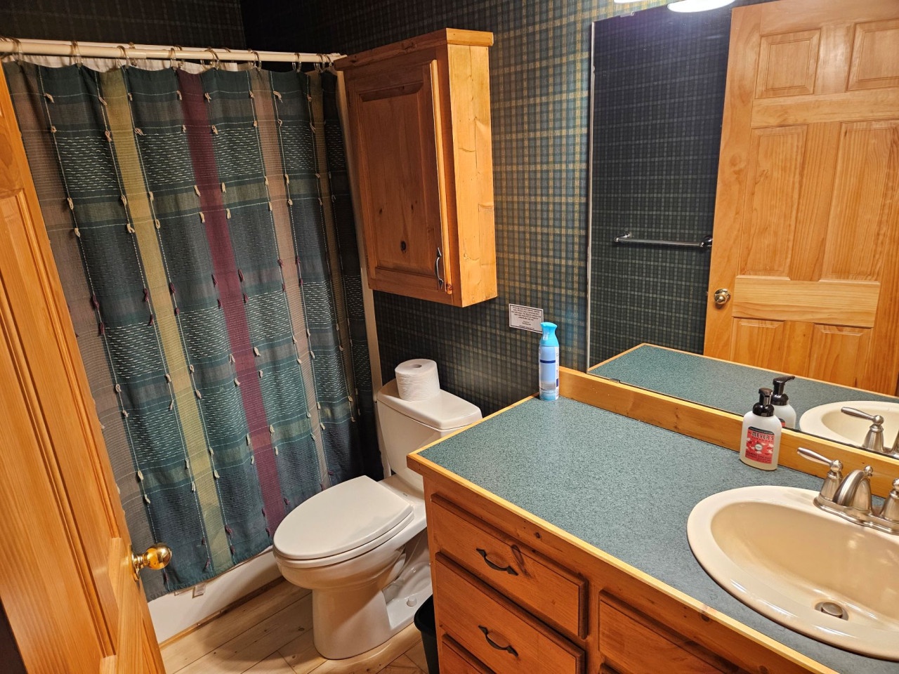 Your private bathroom features warm wood cabinetry, a spacious vanity with ample storage, and a shower-tub combo for relaxing soaks after exploring.