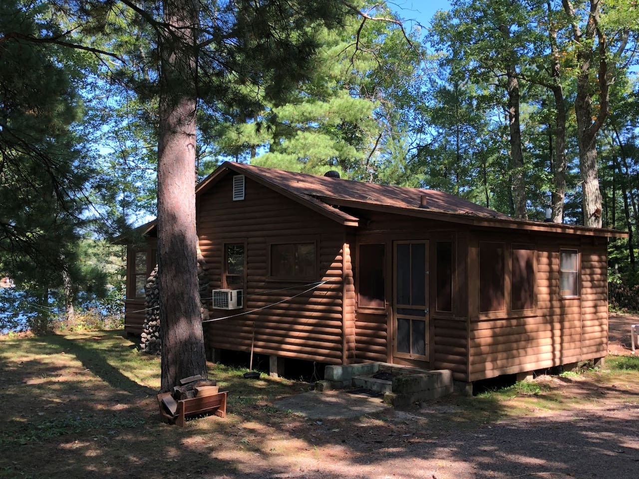 Charming log cabin nestled among towering pines, offering rustic comfort with modern conveniences like air conditioning for your perfect woodland getaway.