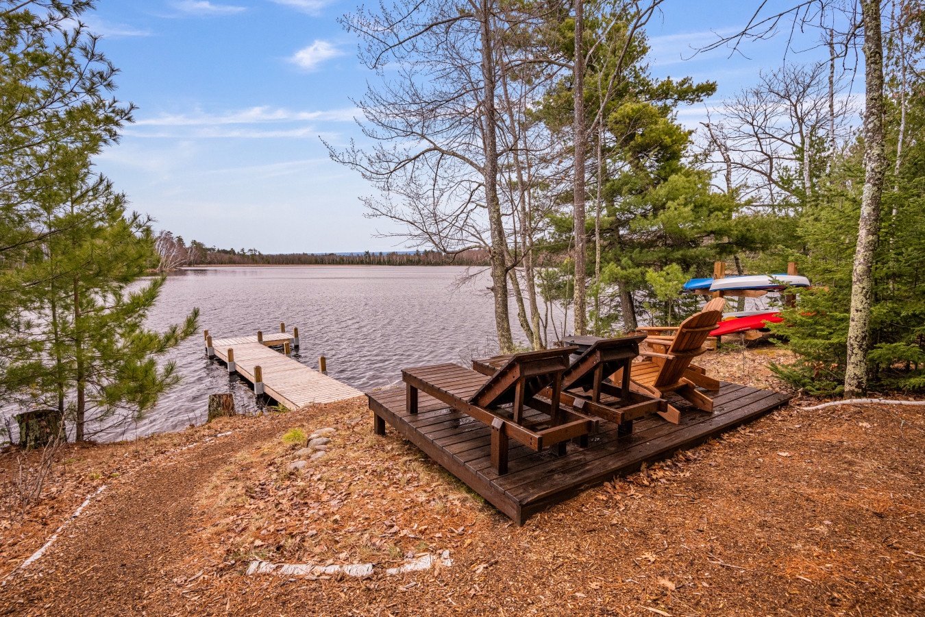 Lakefront deck with Adirondack chairs and private dock surrounded by pristine wilderness - your perfect waterside retreat.