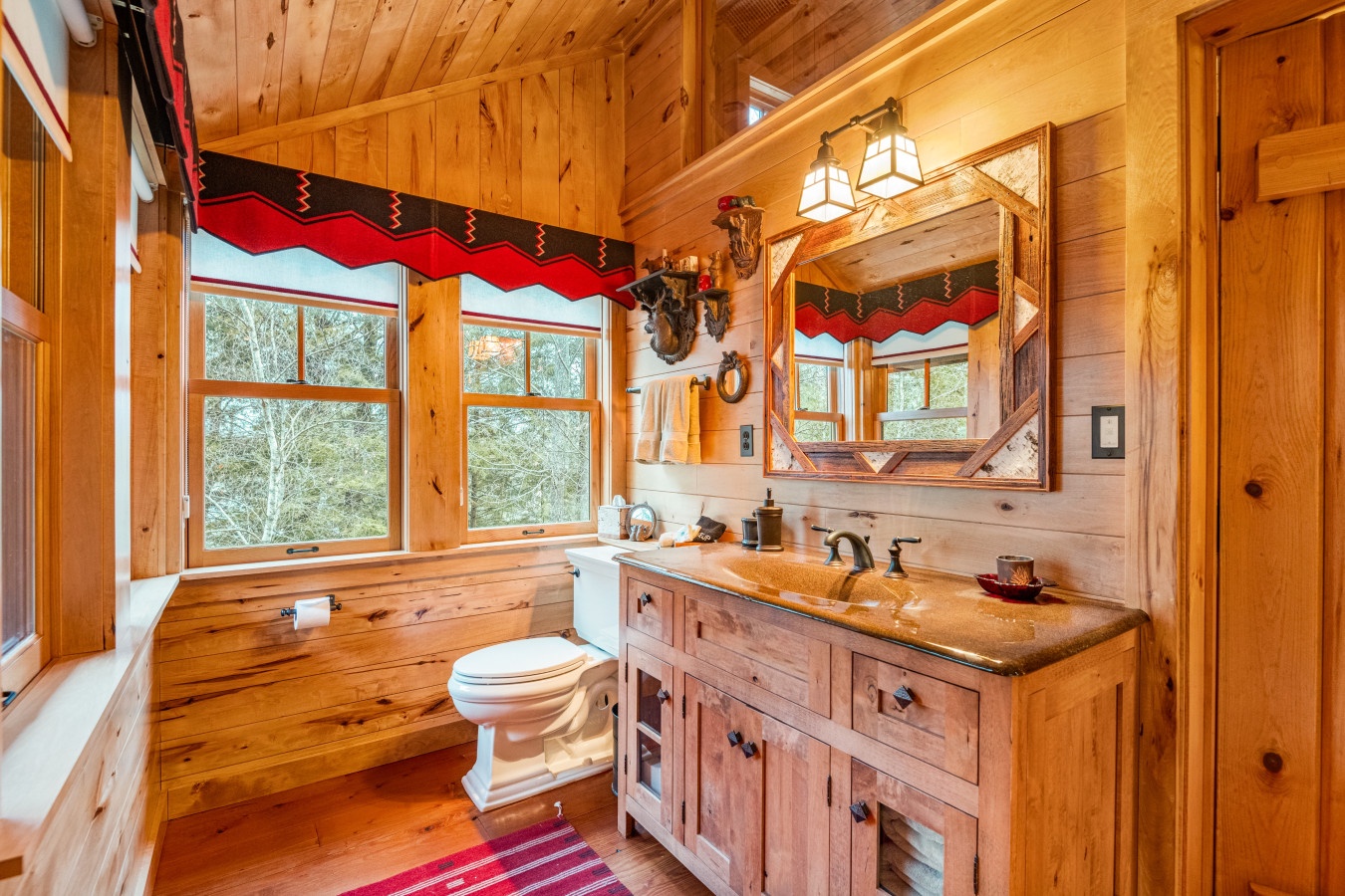 Step into your rustic bathroom retreat where warm wood walls and Native American accents create a cozy cabin atmosphere for unwinding.