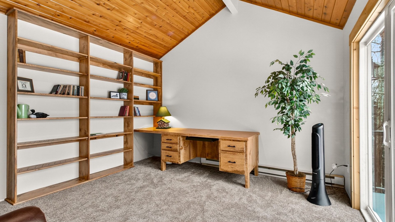 Create your perfect workspace in this bright office with built-in shelving, warm wood ceiling, and peaceful garden views.