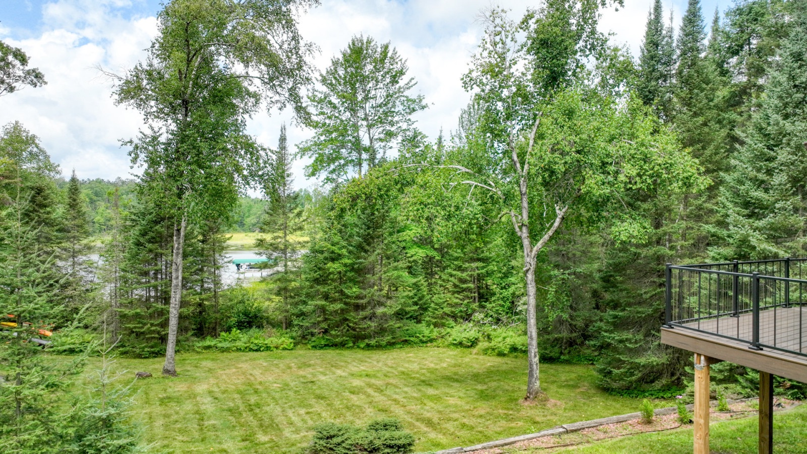Peaceful woodland setting with mature trees, expansive lawn, and tranquil water views creating a serene natural retreat.