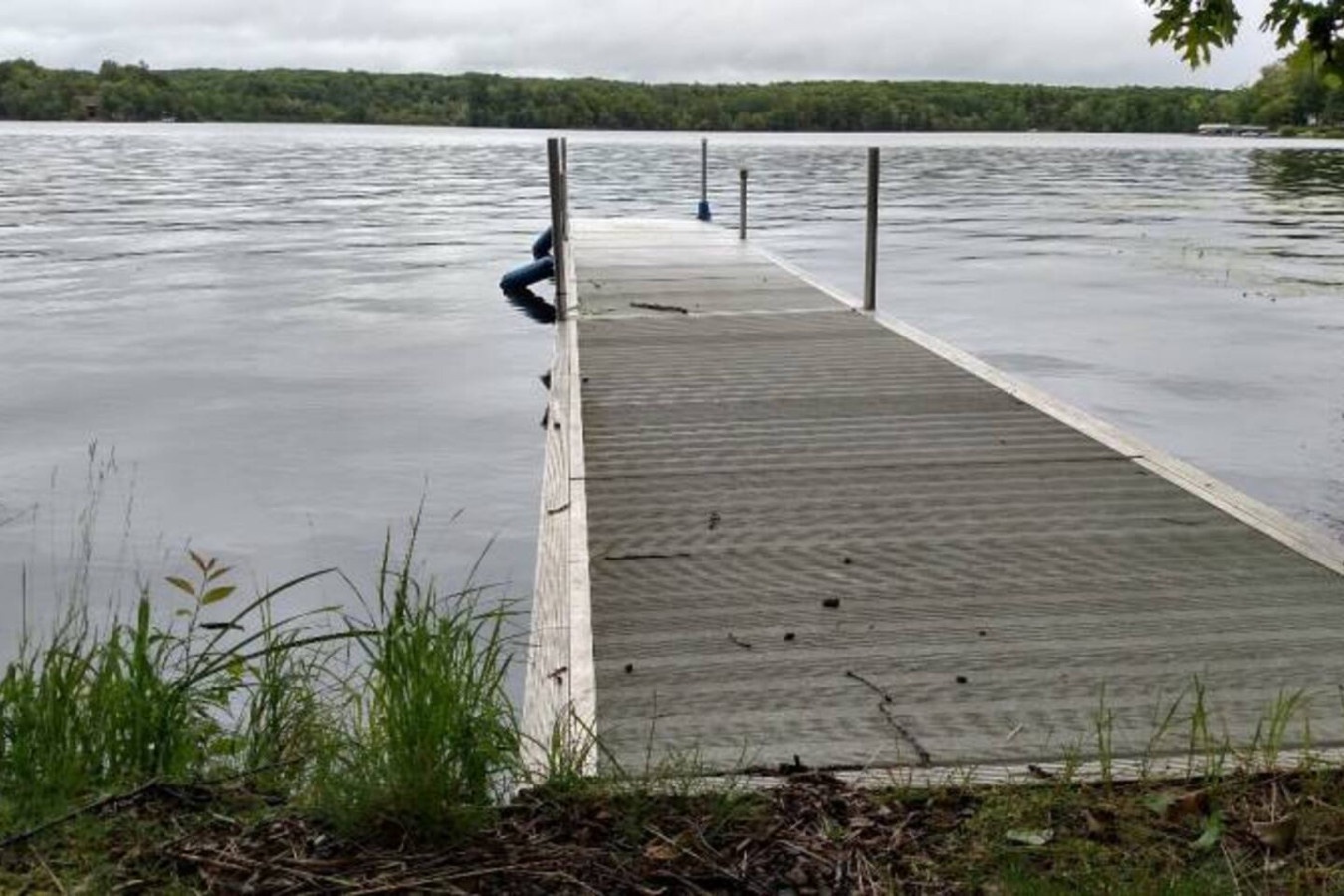 Private dock extends into pristine lake waters, surrounded by dense forest and natural shoreline.