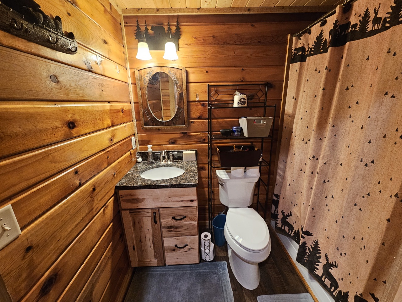 Step into your rustic cabin bathroom where warm wood walls and charming wildlife decor create a cozy forest retreat feeling.