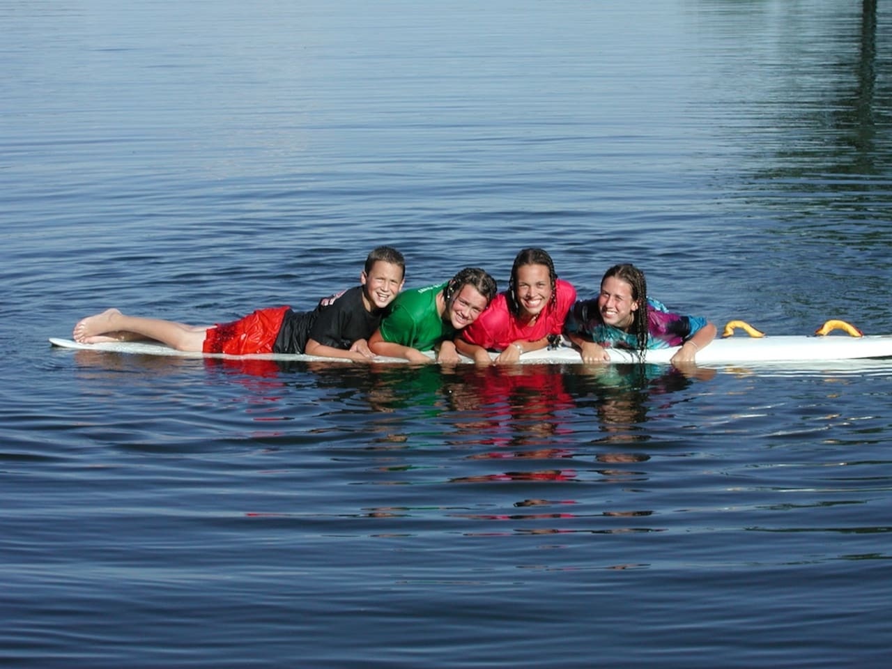 Family enjoys waterfront activities with paddleboard adventures on pristine lake waters near the property.