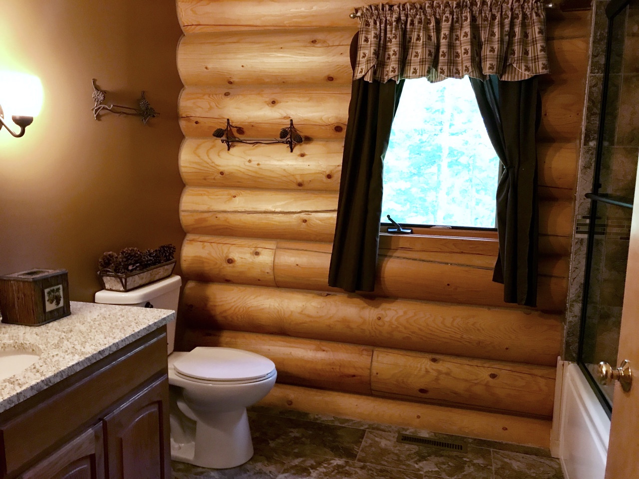 Your private rustic bathroom features warm log cabin walls and granite countertops, creating a cozy mountain retreat atmosphere.