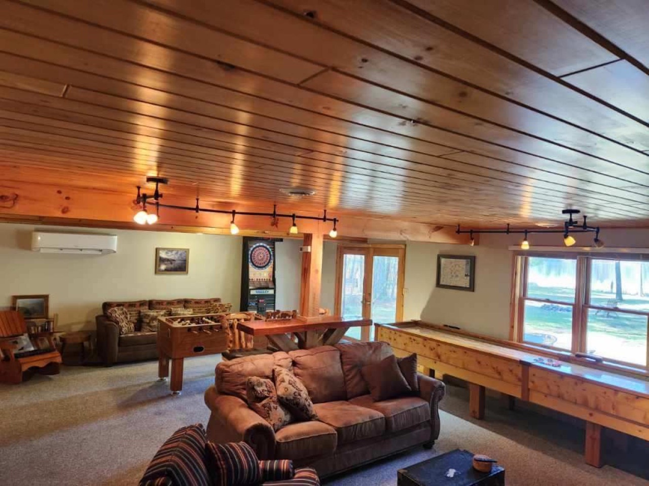 Gather with friends in this warm game room featuring foosball, darts, and cozy seating under rustic wood beams.