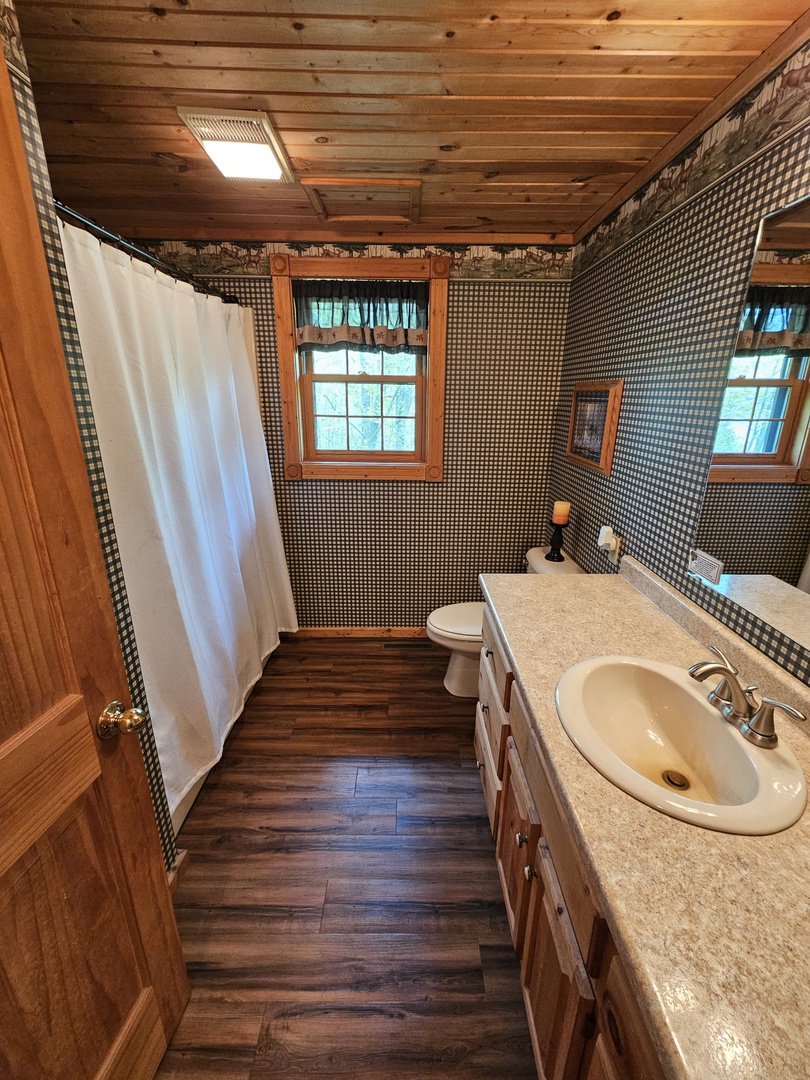 Charming rustic bathroom with exposed wood beams and natural light streaming through windows creates a cozy cabin retreat for your stay.