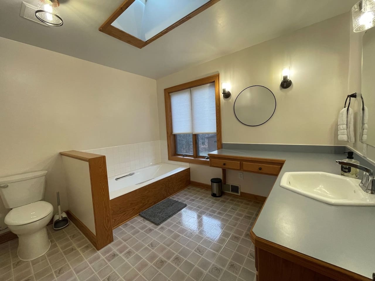 Unwind in your spacious bathroom featuring warm wood accents, skylight views, and a deep soaking tub perfect for relaxation.